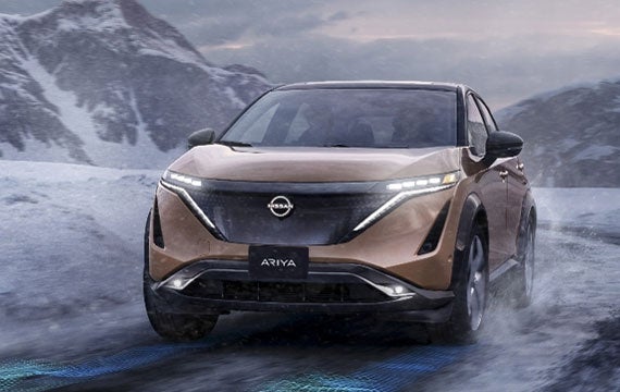 Nissan ARIYA in Sunrise Copper on snowy mountain road | Taylor's Auto Max Nissan in Great Falls MT