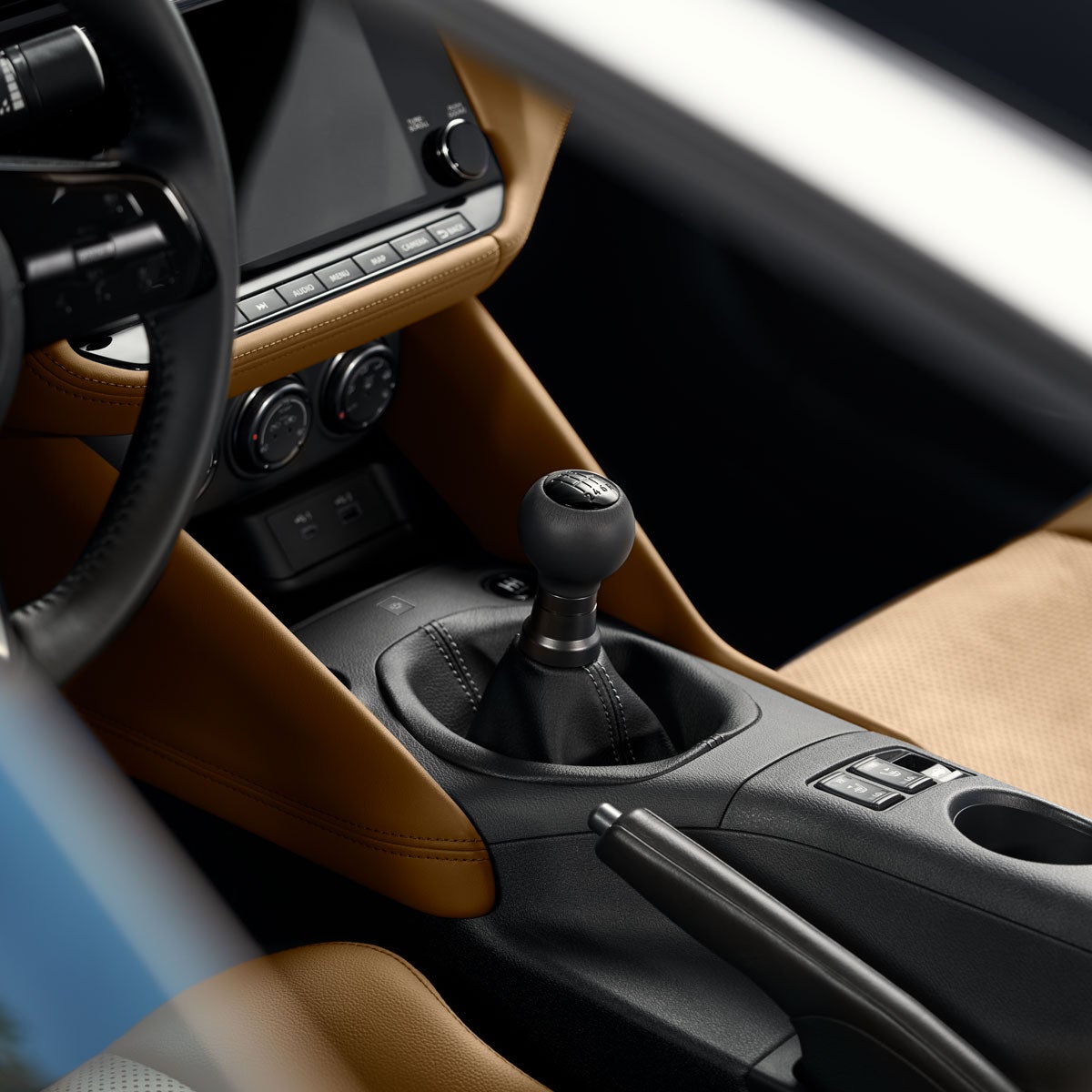 Interior view of a modern sports car with tan seats and dashboard trim, black steering wheel, and a 6-speed manual gear shifter.